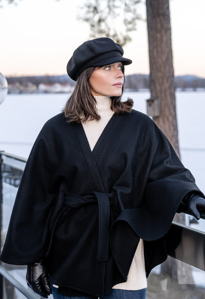 Woman with black cape and hat